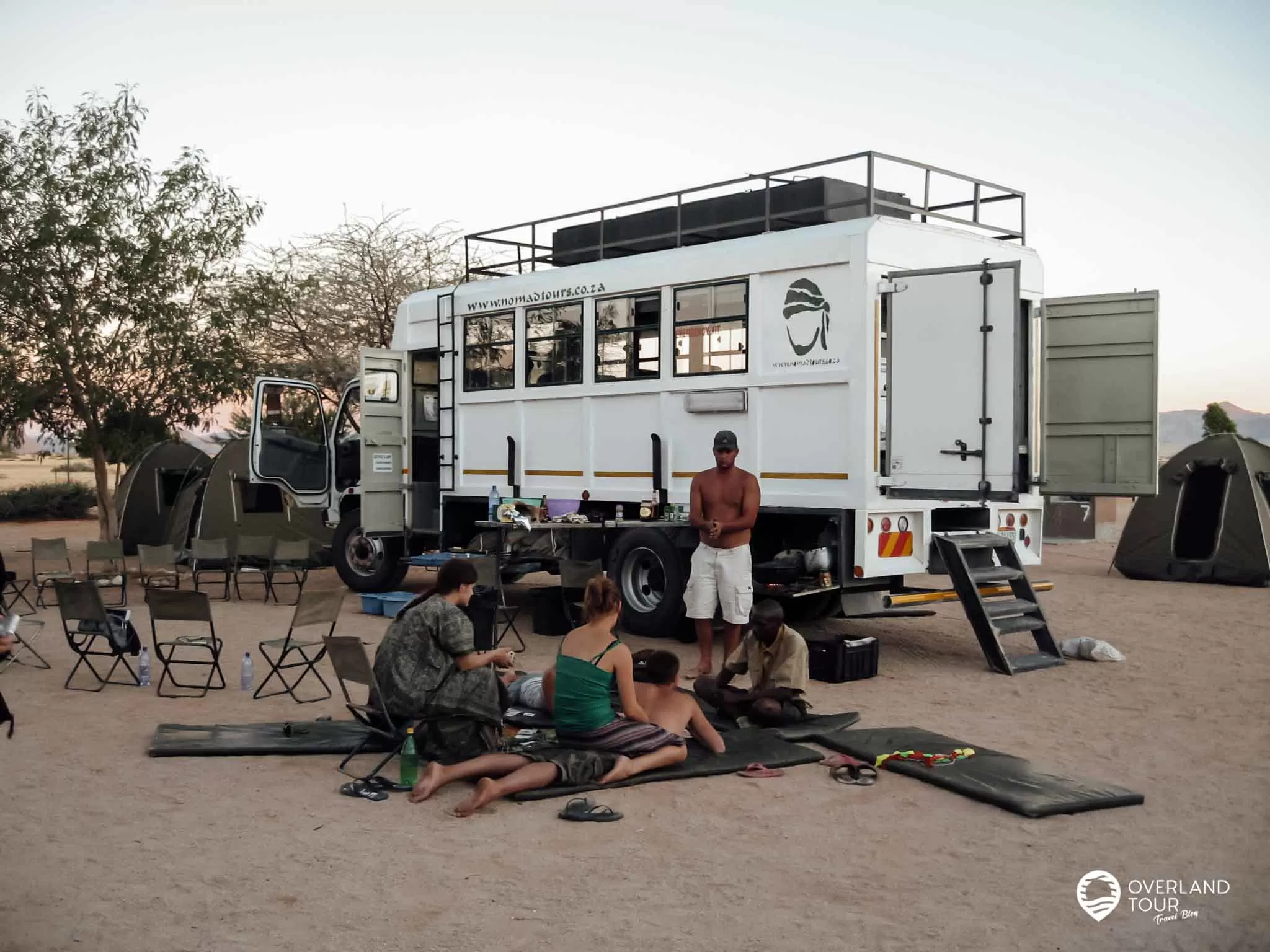 Die Overlander relaxt am Truck - Chillen, unterhalten und auf das leckere Abendessen warten