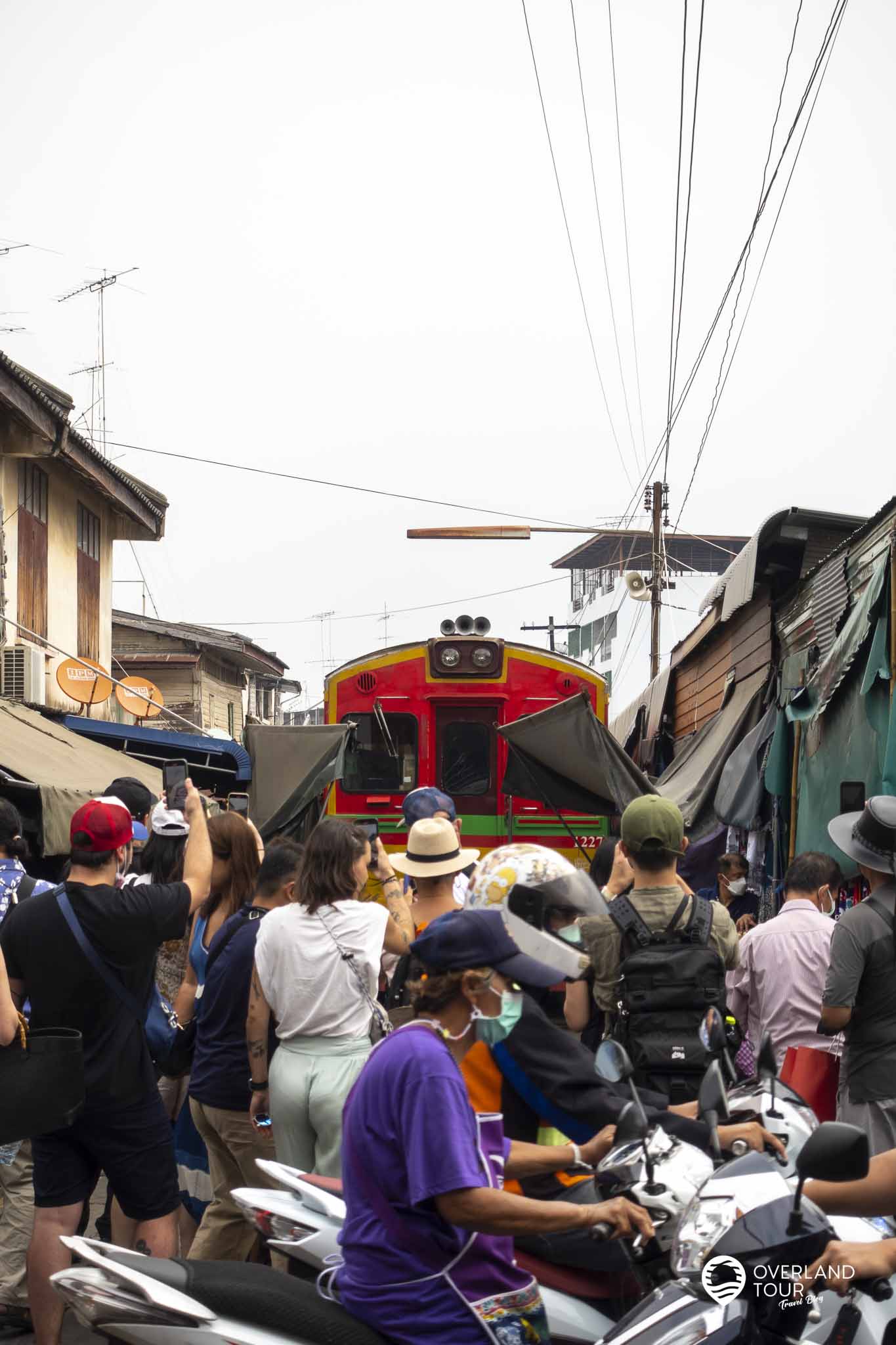 Der Besuch des Maeklong Railway Market bei Bangkok Der Zug zurück verlässt den Bahnhof und sofort nachdem der letzte Wagen einen Marktstand passiert hat, ist dieser schon wieder aufgebaut und auf dem Gleis zurück